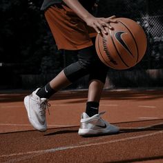 a person holding a basketball on a court with trees in the backgrouds