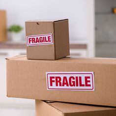 two boxes with fragile stickers on them stacked on top of each other in a room