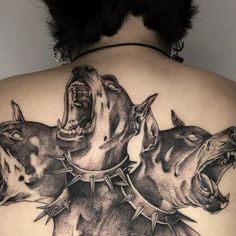 a woman's back with three dogs on it and one dog has its mouth open