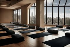 yoga mats are lined up on the floor in front of large windows with panoramic city view