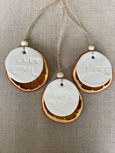 three white ceramic ornaments hanging from twine on a gray cloth background, with the words true fire printed on them