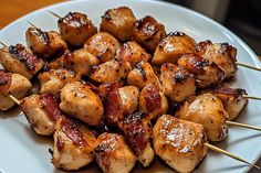 chicken and bacon skewers on a white plate with toothpicks in them