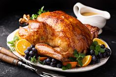 a turkey on a platter with oranges, blueberries and other food items