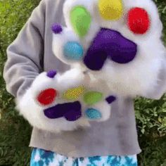 a young boy is holding up his hand painted animal paw mitts in front of some bushes