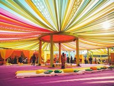 an outdoor wedding with colorful draping on the ceiling and tables in the middle