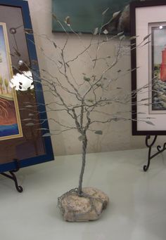 there is a small tree in the middle of a table with two pictures on it