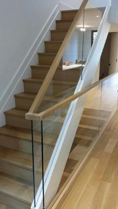 a wooden stair case with glass railing and handrail