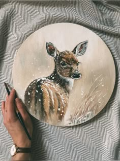 a hand holding a pencil and drawing on a plate with a deer painting on it