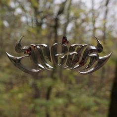 a metal sculpture with butterflies on it in front of trees