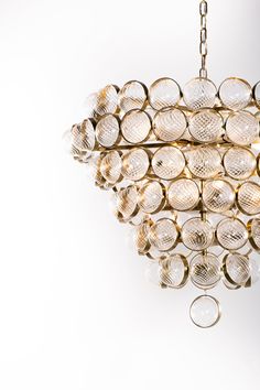 a chandelier made out of glass balls hanging from a chain on a white wall