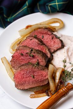 some meat and onions are on a plate with mashed potatoes next to the steak