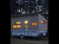 a mobile home is lit up by the windows at night in front of some trees