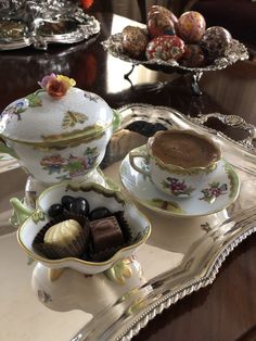 two tea cups and saucers on a tray with chocolates