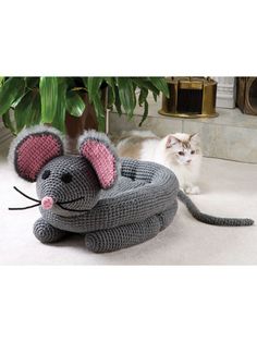 there is a cat sitting next to a crocheted mouse and an elephant toy