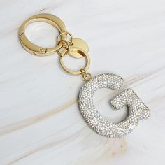 a gold keychain with the letter g on it's front and back sides