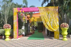 an outdoor wedding venue with yellow drapes and flowers on the aisle, surrounded by palm trees