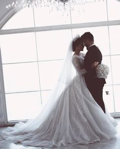 a bride and groom standing in front of a window