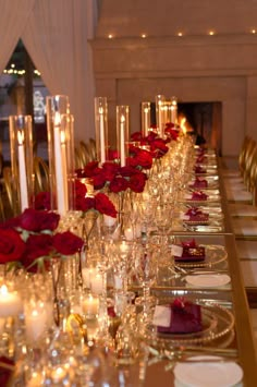 a long table is set with candles and red roses