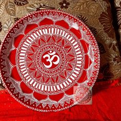 a red and white plate sitting on top of a bed next to a brown pillow