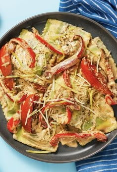 a pan filled with pasta and vegetables on top of a blue table