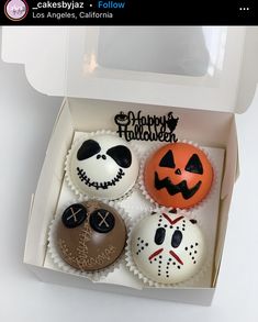 four decorated cupcakes in a box with happy halloween written on them