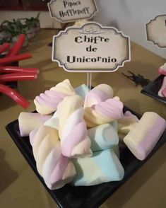 there is a black plate with pink and white marshmallows on it next to a sign that says chiffre de unicorn