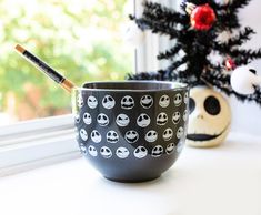 a black and white cup sitting on top of a window sill next to a christmas tree