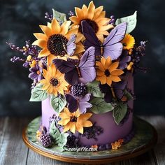 a purple cake with sunflowers and butterflies on top is sitting on a wooden table