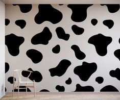 a chair sitting in front of a wall with black and white cow print on it