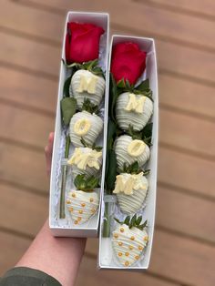 two white chocolate covered strawberries and one red rose in a box with gold trim