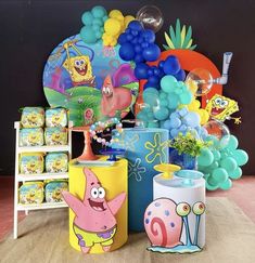 there are many balloons and decorations on the floor in front of this display table with spongebob characters