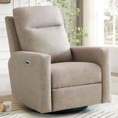 a beige recliner chair sitting on top of a rug in front of a window