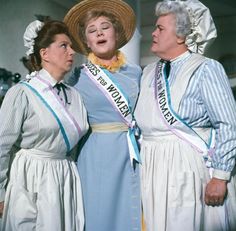 three women in white dresses and hats are standing next to each other with their mouths open