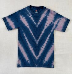 a blue and purple tie - dye shirt with an arrow on the front, sitting on a white surface