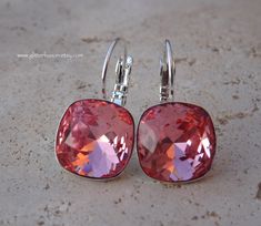 These earrings feature genuine Swarovski crystals in the shade Rose Peach. These stunning peachy-pink crystals have a beautiful sparkle and shine. The cushion cut crystals used in these earrings measure 12mm. They have been hand set into shiny silver plated settings. These earrings measure just under an inch from the top of the ear wire to the bottom of the crystal. They are a nice size and larger than most I have seen. They are simple, elegant and most definitely eye catching! Perfect for bride Bridesmaid Earrings Gift, Summer Bridesmaids, Shade Roses, Crystal Statement Earrings, Rose Peach, Bling Earrings, Earrings Pink, Pink Peach, Silver Spring