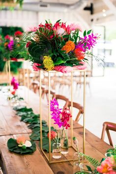 an arrangement of flowers and greenery on a table at a wedding or event with gold stands