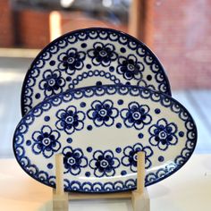 two blue and white plates sitting on top of a wooden stand in front of a brick wall