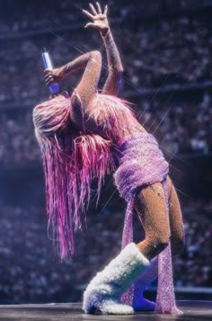 a woman dressed in pink and purple dancing on stage