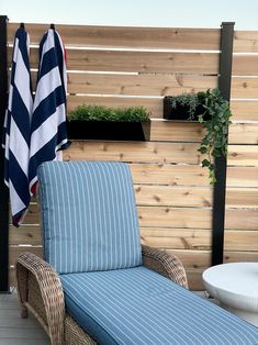 a blue and white striped chaise lounge chair on a wooden deck with potted plants