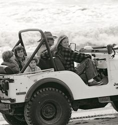 a group of people riding in the back of a jeep on top of a beach