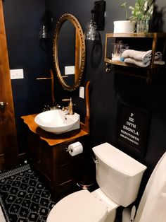 a white toilet sitting next to a sink in a bathroom under a mirror and wooden cabinet