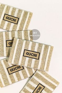 four pieces of gold and white striped fabric with guchi written on the side in black ink