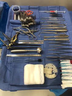 an assortment of surgical tools are displayed on a blue tablecloth with other medical supplies