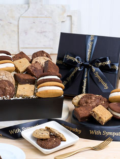 assorted cookies and pastries are on display in front of a black box with a bow