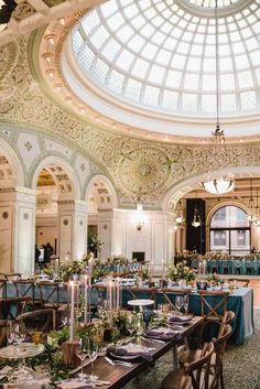 an ornately decorated dining room with blue linens and greenery on the tables