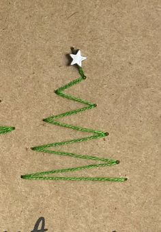 a small christmas tree made out of string on top of a piece of brown paper