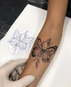 a woman's arm with a black and white butterfly tattoo on the left wrist