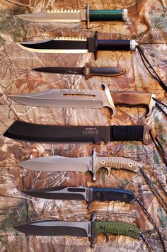 several knives are lined up on a camouflage sheet