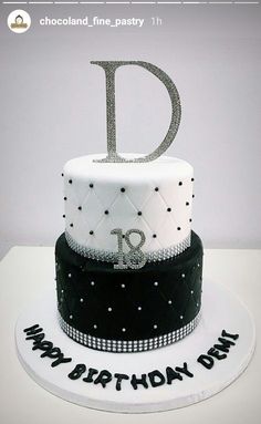 a white and black birthday cake with the letter d on it