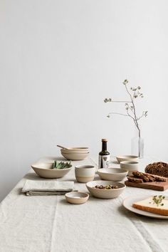 a table topped with plates and bowls filled with food next to a bottle of wine